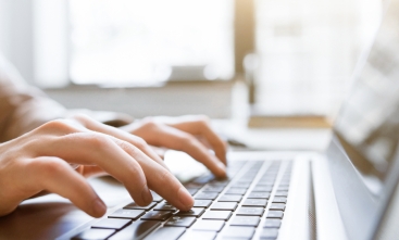 Mãos digitando em um teclado de notebook