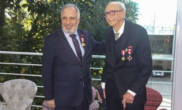 Dois homens de terno posam para foto, sorridentes, com medalhas cravadas no paletó.