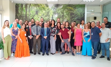 Fotografia de um grupo de trinta pessoas em pé sorrindo para a foto.