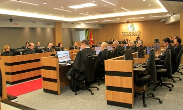 Fotografia da sala de sessões do pleno. Sentados, diante de microfones e telas de computadores, homens e mulheres de toga estão concentrados.