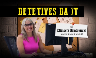 Detetives da JT: Elizabete Dombrowski, servidora da Caex de Rio do Sul. Uma mulher de blusa cor de rosa, loira, sorrindo em frente a um monitor. Ao fundo, um quadro com diversos papeis pendurados, como se estivesse em uma delegacia.