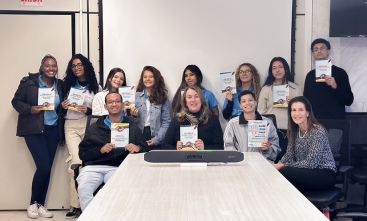 Jovens segurando cartilha sobre assédio moral