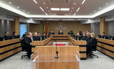 Fotografia da sala de sessões do pleno. Sentados, diante de microfones e telas de computadores, homens e mulheres de toga estão concentrados.