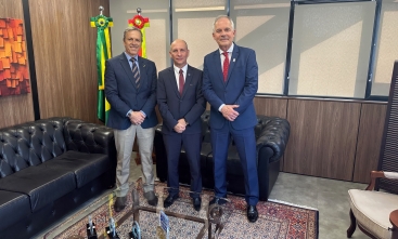 Três homens de terno e gravata estão em pé posando para a foto