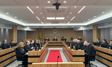 Fotografia da sessão do pleno em que a tese jurídica foi aprovada.  Homens e mulheres estão sentados diante de computadores, vestindo togas.