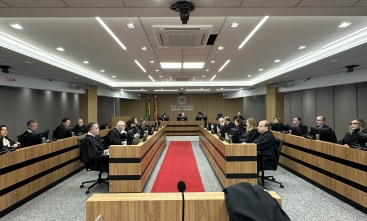 Foto de uma sala de sessões de julgamento composta por magistrados e magistradas de toga