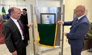 Dois homens de terno e gravata estão descerrando uma placa de inaguração