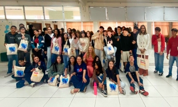 Mais de 40 jovens e três mulheres adultas estão sorrindo e posando para a foto