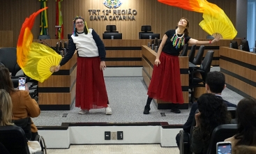 Duas jovens dançando com vestido vinho e lenços vermelhos e amarelos