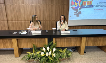 Foto de duas mulheres sentadas fazendo uma palestra