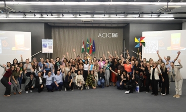 Grupo de pessoas reunidas e sorrindo em auditório da ACIC, com bandeiras ao fundo e clima de celebração.