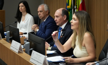 Grupo de quatro pessoas sentadas em uma bancada, como em uma mesa de abertura de evento