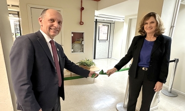 Uma mulher e um homem estão descerrando uma faixa de inauguração