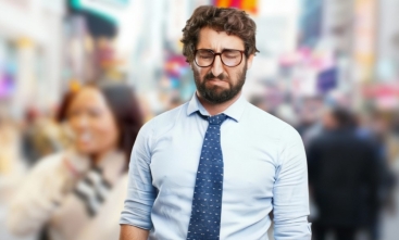 Fotografia ilustrativa de homem jovem em primeiro plano, com expressão chateada