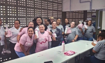 Grupo de mulheres posam para a foto. Algumas delas usam camisetas rosas do Outubro Rosa.