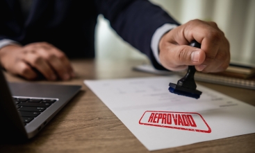 Arte ilustrativa de uma folha de papel sendo carimbada com a palavra "reprovado"