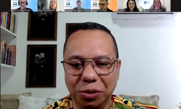 Rosto de um homem negro, de óculos, cabelo curto, falando em uma videoconferência