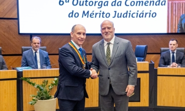 Dois homens de terno se cumprimentam e posam para foto. 