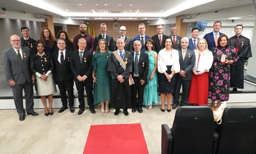 25 pessoas posam para foto em uma sala de sessões de julgamento