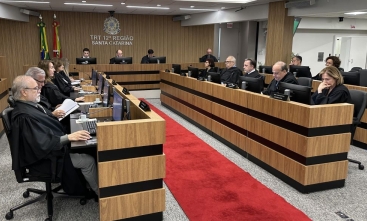 Sala de sessões de um tribunal mostrando 19 pessoas sentadas em uma mesa em formato de U
