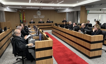 Sala de sessões de um tribunal mostrando 19 pessoas sentadas em uma mesa em formato de U