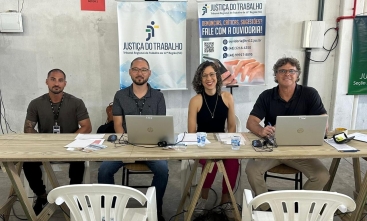 Imagem de uma mulher e três homens sentados em uma mesa com computador