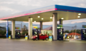 Fotografia ilustrativa com pouca nitidez de um posto de gasolina com movimento durante o dia