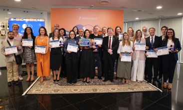 Grupo de cerca de 30 pessoas posam para foto, de pé, exibindo certificados e troféus.