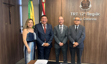 Uma mulher e três homens estão em pé, posando para a foto