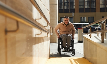 Homem em cadeira de rodas subindo rampa de acesso