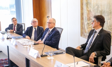Quatro homens de terno sentados à mesa de um evento