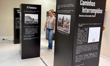 Mulher ruiva observa totens de uma exposição.