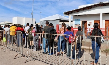 Imagem mostra uma fila de pessoas no que parece ser um posto de imigração