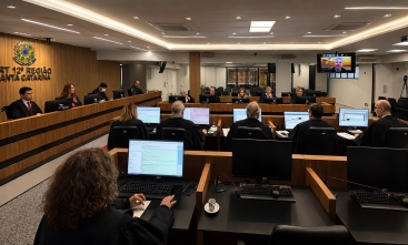 Foto de uma reunião no tribunal pleno do TRT-SC com os desembargadores nas mesas com computadores ligados