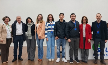 Cinco mulheres e quatro homens estão lado a lado posando para a foto