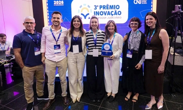 Dois homens e cinco mulher posam para foto segurando premiação