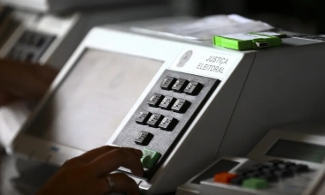 Urna eletrônica branca, com uma digitando um número