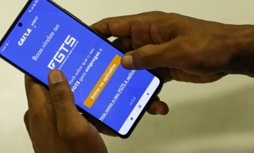 Foto de um smart phone com uma imagem na tela do banco caixa econômica (FGTS)