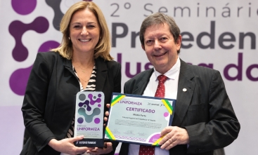 Homem e mulher posam para a foto segurando premiação