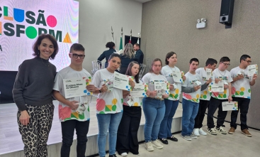 Mulher posa com 10 jovens lado a lado. Todos eles exibem um certificado.