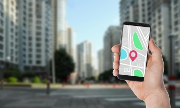 Mão segura um celular com a imagem do Google Street View com imagens distorcidas de prédios ao fundo