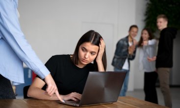 Homem humilha mulher no ambiente de trabalho, em uma cena que é observada pelos colegas