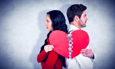 Casal de namorados, um de costas para o outro, segurando uma imagem de um coração rasgado
