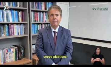 homem de pé vestindo terno falando em um ambiente com livros