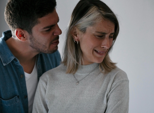 Foto de um homem branco brigando com uma mulher branca. Ela está triste.