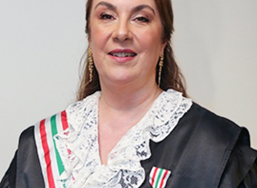 Foto de uma mulher branca vestida de beca e uma medalha no peito