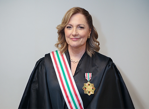 Foto de uma mulher branca vestida de beca e uma medalha no peito