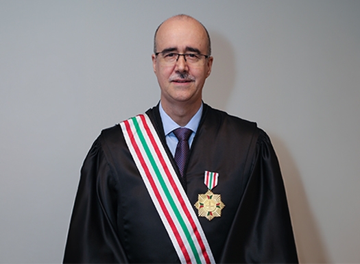 Foto de um homem branco vestido de beca e uma medalha no peito