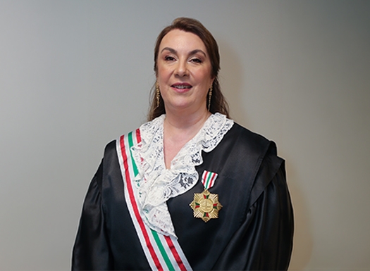 Foto de uma mulher branca vestida de beca e uma medalha no peito