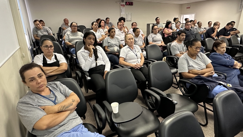 Foto de homens e mulheres assistindo uma palestra